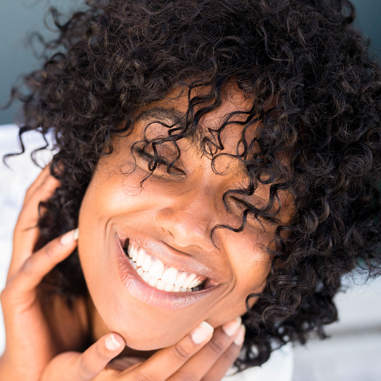 A woman smiling with bright white teeth after whitening
